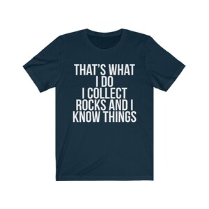 Puede incluir: Una camiseta azul marino con texto blanco que dice "That's what I do I collect rocks and I know things."