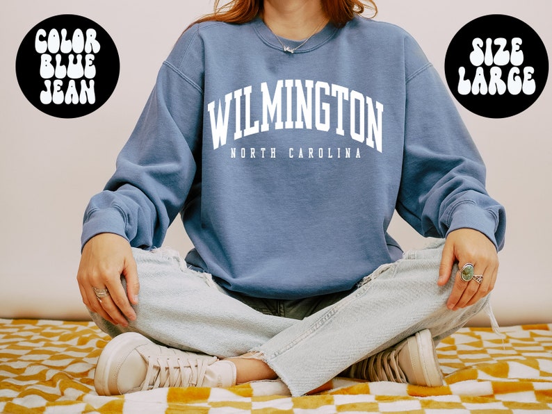 May include: A blue sweatshirt with the text "WILMINGTON NORTH CAROLINA" in white. The sweatshirt is a large size.