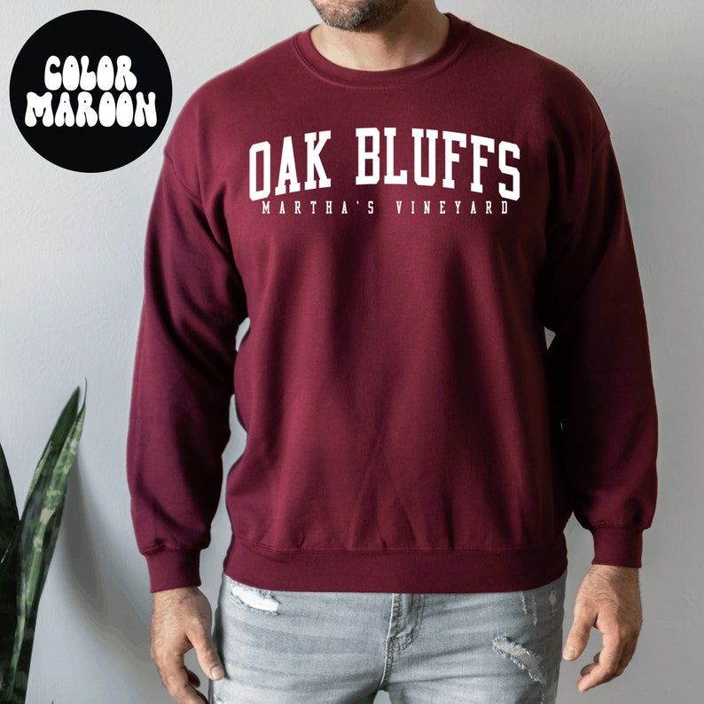 Op de afbeelding: Een bordeauxrood sweatshirt met witte tekst die "Oak Bluffs Martha's Vineyard" zegt.