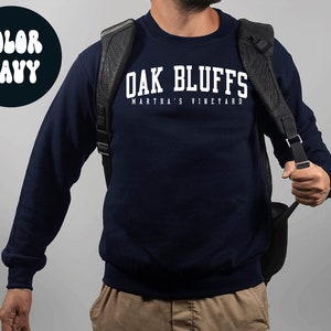 Op de afbeelding: Een marineblauw sweatshirt met witte tekst die "Oak Bluffs Martha's Vineyard" zegt.