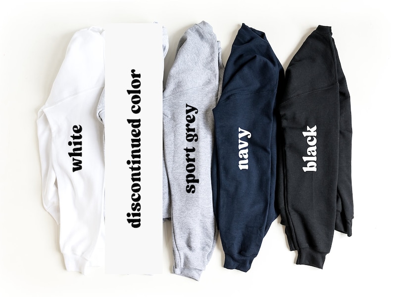 May include: Five long-sleeved shirts in different colors: white, sport grey, navy, black, and a discontinued color. The shirts are folded and laid out on a white surface.