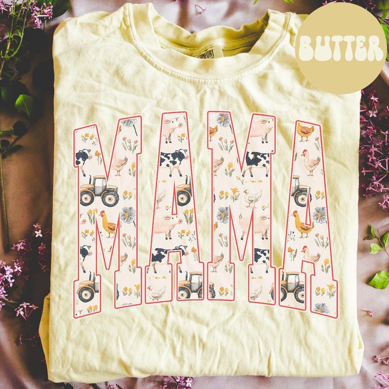 A yellow t-shirt with the word "MAMA" printed on it, surrounded by various farm-themed illustrations such as tractors, animals, and flowers.