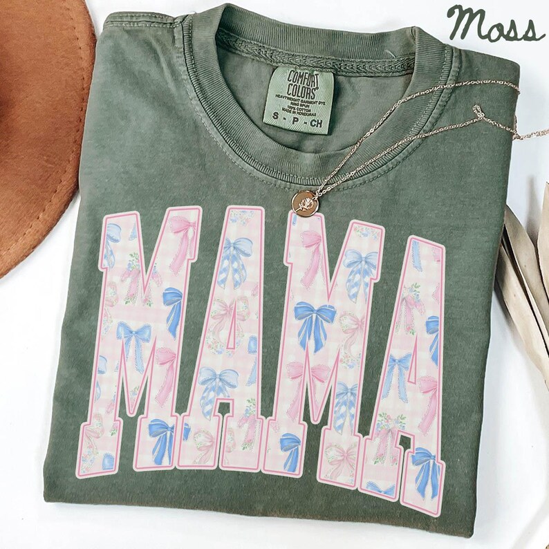 a green t-shirt with the word "MAMA" printed on it, along with a necklace and a brown hat.