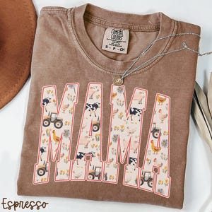 A brown t-shirt with the word "MAMA" printed on it, featuring various farm and animal-themed illustrations.