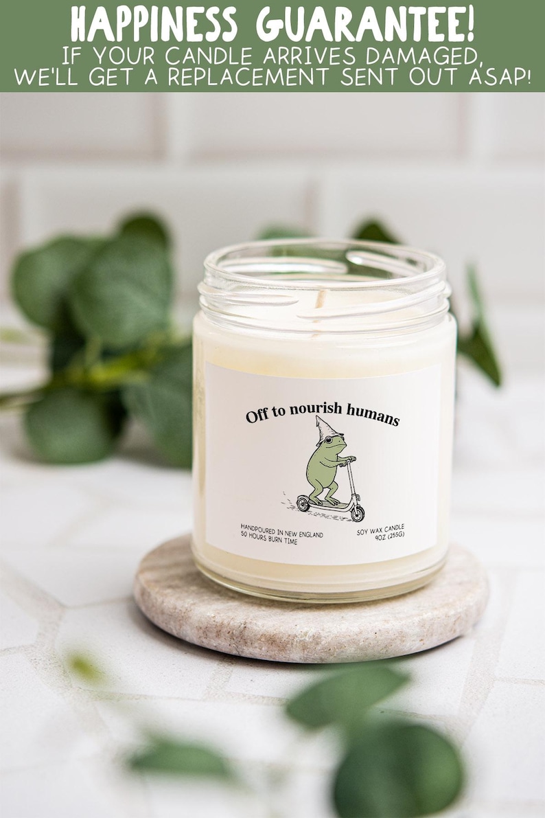 a candle labeled "Off to nourish humans" with a frog illustration, placed on a small stone or coaster.