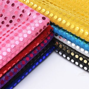 May include: A stack of colorful fabric with sequins in various colors, including pink, red, purple, blue, silver, black, and gold. The fabric is made of a mesh material with small, round sequins.
