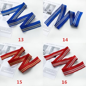 May include: Four samples of elastic trim with gold and silver stripes. The trim is blue, red, blue, and red. The trim is arranged in a zig-zag pattern. The numbers 13, 14, 15, and 16 are printed below each sample.