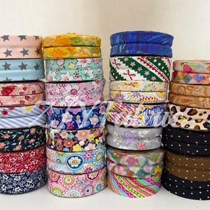 May include: A selection of fabric-covered headbands in a range of patterns and colours. Designs include stars, florals, stripes, and polka dots. The headbands are stacked in multiple piles, displaying the variety of styles.