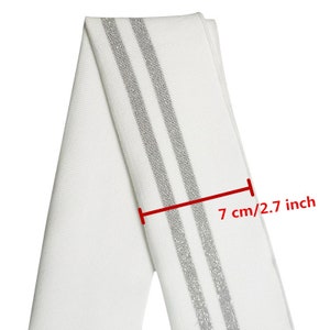 May include: White fabric with two silver stripes. The fabric is 2.7 inches wide.
