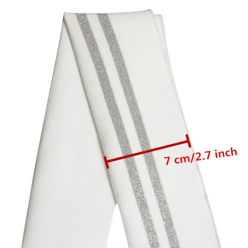 May include: White fabric with two silver stripes. The fabric is 2.7 inches wide.