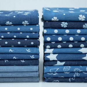 May include: A stack of blue denim fabric squares with different patterns, including flowers, polka dots, stars, and fruit. The fabric is perfect for quilting, crafts, and other sewing projects.
