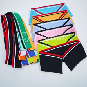 Op de afbeelding: Een verzameling kleurrijke gebreide sierstukken in verschillende kleuren, waaronder zwart, rood, wit, groen, blauw, geel en roze. De sierstukken hebben strepen en contrasterende randen, geschikt voor kleding en knutselprojecten.