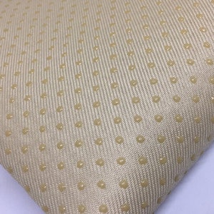 Op de afbeelding: Beige stof met een subtiel textuurpatroon van kleine, verhoogde stippen.