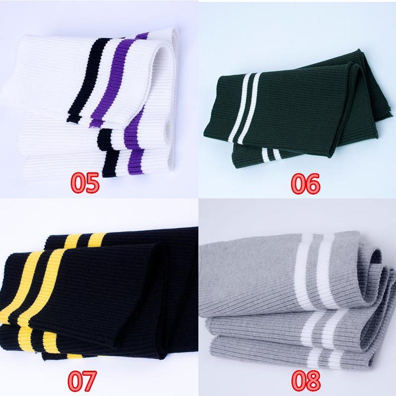May include: Four pairs of folded knit leg warmers in various colors. White with black and purple stripes, dark green with white stripes, black with yellow stripes, and gray with white stripes. Each pair has a number printed on it.