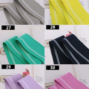 May include: Five different colors of elastic trim with white stripes. The colors are gray, yellow, green, navy blue, and purple. The trim is 25, 26, 27, 28, and 29.