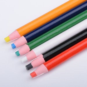 May include: Six marking pencils with different coloured tips: orange, blue, green, white, black, and red. The pencils have a pink rubber grip.