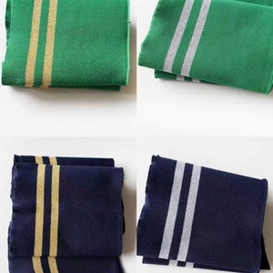 May include: Four folded rectangular cloths in green and navy blue. Two cloths are green with gold stripes, and two are green with silver stripes. The other two cloths are navy blue with gold stripes, and the last two are navy blue with silver stripes.