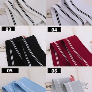 May include: Six samples of double-striped elastic trim in different colors: white with black stripes, black with white stripes, red with white stripes, light blue with white stripes, gray with white stripes, and white with black stripes.