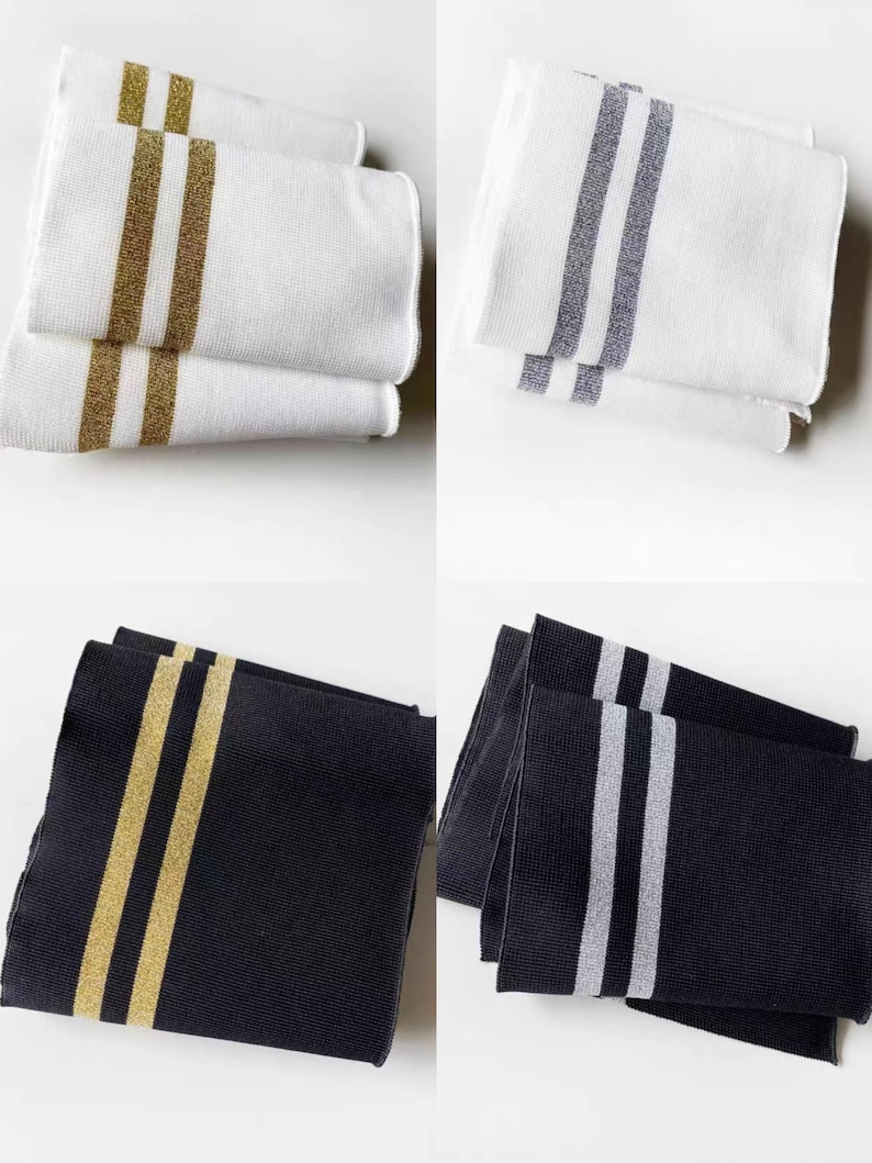 May include: Four sets of decorative towels. Two sets are white with gold or silver stripes. The other two sets are black with gold or silver stripes. The towels are folded and stacked, showcasing the striped design.