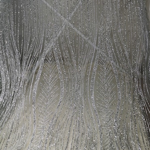 May include: Silver glitter fabric with a wavy, abstract pattern. The fabric has a subtle sheen and a delicate texture.