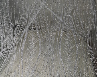May include: Silver glitter fabric with a wavy, abstract pattern. The fabric has a subtle sheen and a delicate texture.