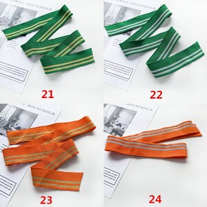 May include: Four different types of elastic trim with two stripes of gold or silver glitter. The trim is green, orange, and white.