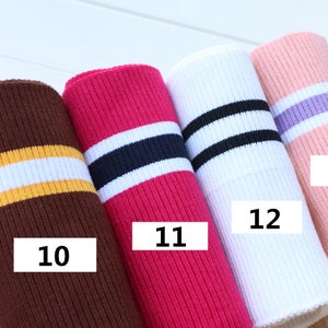 Puede incluir: Cuatro tejidos de punto de canal&eacute; de diferentes colores con rayas contrastantes. Los colores son marr&oacute;n con rayas amarillas y blancas, rosa con rayas azul marino y blancas, blanco con rayas negras y rosa con rayas moradas y blancas. El tejido est&aacute; etiquetado con los n&uacute;meros 10, 11, 12 y 13.