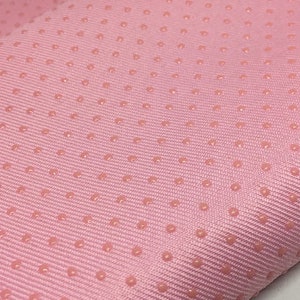 Op de afbeelding: Roze stof met een subtiel textuurpatroon van kleine, verhoogde stippen.