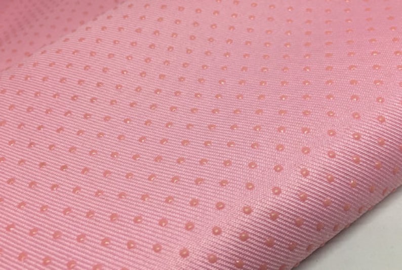 Op de afbeelding: Roze stof met een subtiel textuurpatroon van kleine, verhoogde stippen.