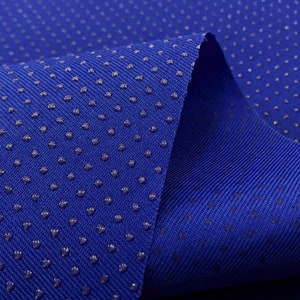 Op de afbeelding: Close-up van een blauwe stof met een textuur. De stof heeft een patroon van kleine, verhoogde stippen.