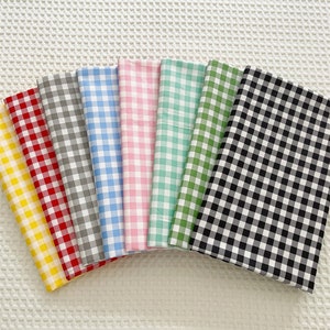 May include: Eight fabric swatches with a gingham pattern in various colours, including yellow, red, grey, light blue, pink, green, and black and white.