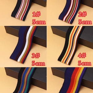 May include: Six different striped elastic bands, each 5 cm wide, with various color combinations. The bands are displayed on black boxes with white text labels indicating the number and size of each band.