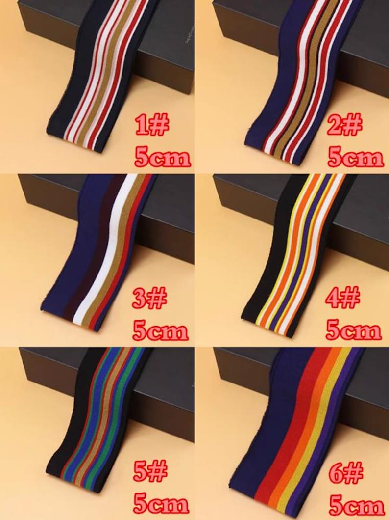 May include: Six different striped elastic bands, each 5 cm wide, with various color combinations. The bands are displayed on black boxes with white text labels indicating the number and size of each band.