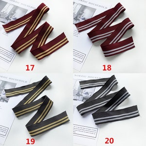 May include: Four different types of elastic trim with two stripes. The trim is available in burgundy with gold stripes, gray with silver stripes, dark gray with gold stripes, and black with silver stripes. The trim is labeled with numbers 17, 18, 19, and 20.