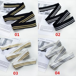 May include: Four samples of elastic trim with two stripes. The trim is available in black with gold stripes, white with gold stripes, white with silver stripes, and black with silver stripes.