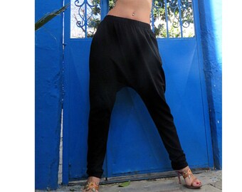 May include: Black harem pants with a loose, flowing fit. The pants have a wide leg opening and a low rise.