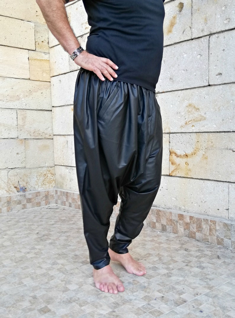 May include: Black leather pants with a loose, gathered fit around the waist and legs. The pants have a shiny, almost wet look.