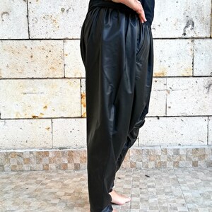 May include: Black leather pants with a loose, flowing fit. The pants have a wide leg and a low rise.