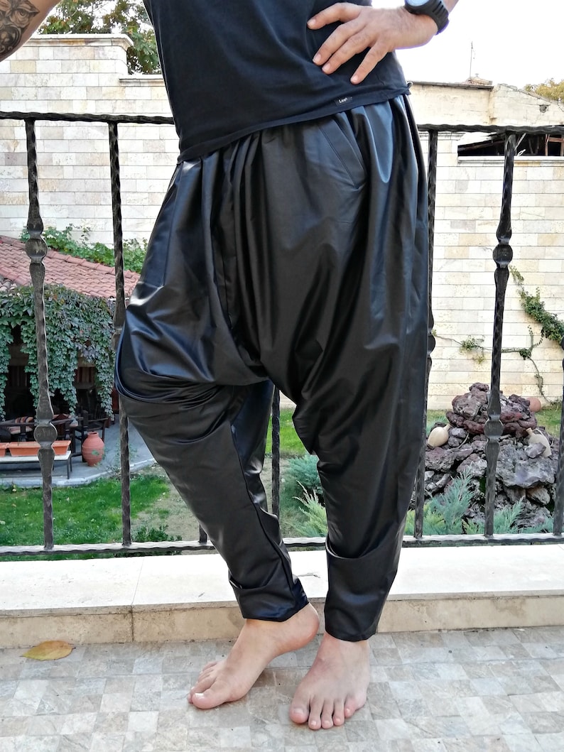 May include: Black leather pants with a loose, gathered fit around the waist. The pants have a slim leg and a cuffed hem.