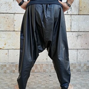 May include: Black leather pants with a loose, flowing fit. The pants have a gathered waistband and a wide leg.