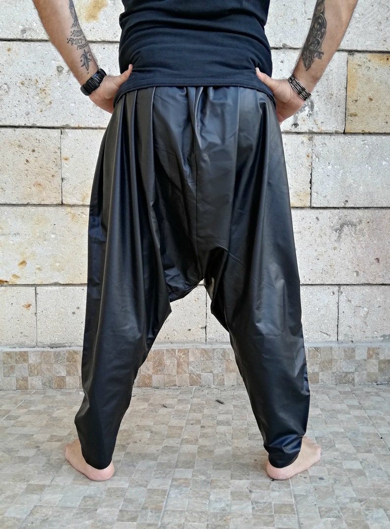 May include: Black leather pants with a loose, flowing fit. The pants have a gathered waistband and a wide leg.
