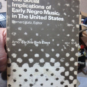 May include: A black and white book cover with the title "The Social Implications of Early Negro Music in The United States" by Bernard Katz, Editor. The book is published by Arno/The New York Times and costs $2.45.
