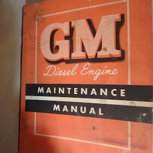 May include: An orange cover for a GM Diesel Engine Maintenance Manual. The cover has the text "GM Diesel Engine Maintenance Manual" and the number "1989" written in black.