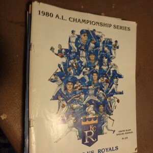 May include: A vintage 1980 American League Championship Series program featuring the Kansas City Royals and the New York Yankees. The cover features a collage of Royals players in their blue uniforms with the team logo and the text "Grand Slam Special Edition $1.25".