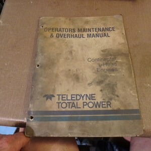 May include: A brown, worn manual titled "Operators Maintenance & Overhaul Manual" for Continental L-Head Engines. The manual is for Teledyne Total Power.