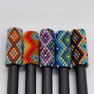 May include: Five wooden knitting needles with colorful beaded tips. The beads are in geometric patterns of orange, blue, green, purple, and brown.