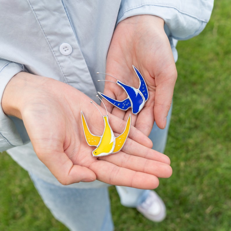 a girl holds stained glass bird pins