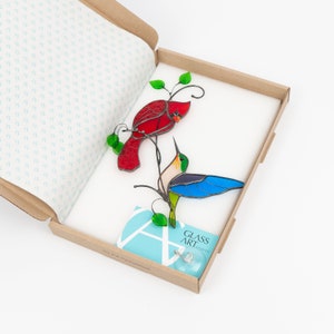 the pair of cardinal + hummingbird stained glass window hanging in the brand box of Glass Art Stories