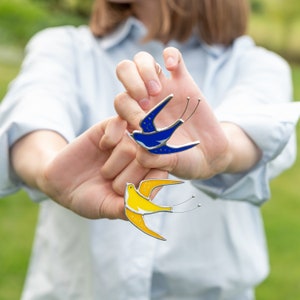 yellow and blue pins of birds made of stained glass