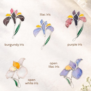 Stained glass flower brooch collection showing different designs of iris flower, handmade botanical jewelry pins assortment, floral gift options.
